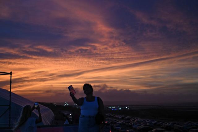 A woman makes a selfie with the sunset in the background during the Legends Football Tournament in Willemstad, Curacao, in the Dutch Caribbean, on April 8, 2026. (Photo by Raul ARBOLEDA / AFP)