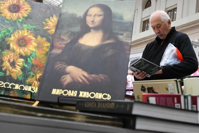 A man reads a book with books about art and painting in the foreground at the Non/Fiction book fair in Moscow on April 9, 2026. (Photo by Igor IVANKO / AFP)