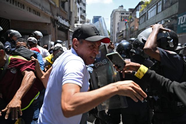 Opponents to the government of Venezuelan interim President Delcy Rodriguez clash with the police as they demonstrate in demand of salary and pension raises in Caracas on April 8, 2026. (Photo by Juan BARRETO / AFP)