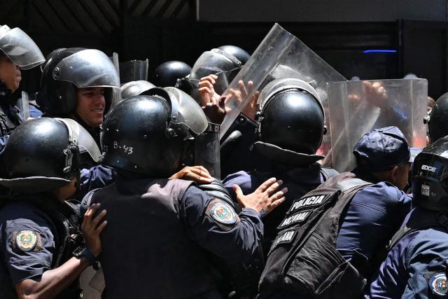 TOPSHOT - Police officers confront opponents to the government of Venezuelan interim President Delcy Rodriguez during a demonstration in demand of salary and pension raises in Caracas on April 8, 2026. (Photo by Juan BARRETO / AFP)