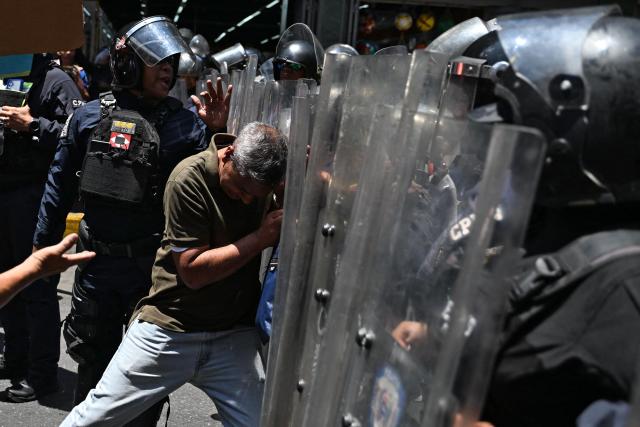 An opponent to the government of Venezuelan interim President Delcy Rodriguez clashes with the police as he demonstrates in demand of salary and pension raises in Caracas on April 8, 2026. (Photo by Juan BARRETO / AFP)
