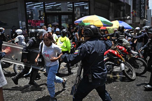 TOPSHOT - Police officers are deployed as opponents to the government of Venezuelan interim President Delcy Rodriguez demonstrate in demand of salary and pension raises in Caracas on April 8, 2026. (Photo by Juan BARRETO / AFP)