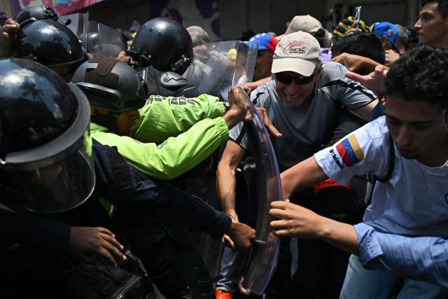 Opponents to the government of Venezuelan interim President Delcy Rodriguez clash with the police as they demonstrate in demand of salary and pension raises in Caracas on April 8, 2026. (Photo by Juan BARRETO / AFP)