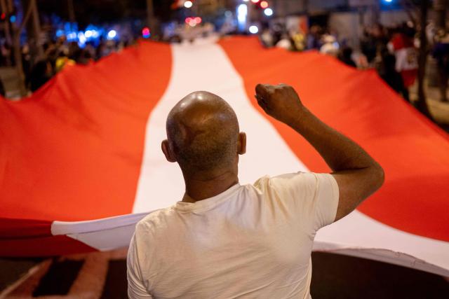 (FILES) A demonstrator displays a a giant Peruvian flag during a protest against the government of Peru's President Jose Jeri in Lima on November 14, 2025. Decisive yet disillusioned, Peru's young people will be key in the April 12, 2026, election to choose a president from a record field of 35 candidates, but with no options that excite them. (Photo by Ernesto BENAVIDES / AFP)
