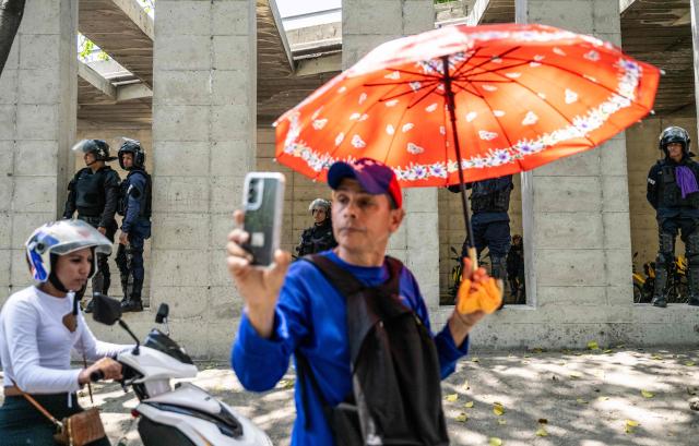 An opponent to the government of Venezuelan interim President Delcy Rodriguez uses a mobile phone during a demonstration in demand of salary and pension raises in Caracas on April 9, 2026. (Photo by Juan BARRETO / AFP)
