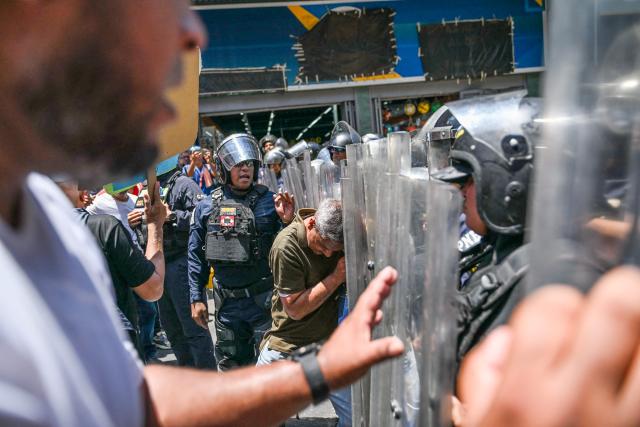 Opponents to the government of Venezuelan interim President Delcy Rodriguez clash with the police as they demonstrate in demand of salary and pension raises in Caracas on April 9, 2026. (Photo by Juan BARRETO / AFP)