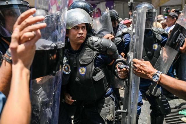 Opponents to the government of Venezuelan interim President Delcy Rodriguez confront the police as they demonstrate in demand of salary and pension raises in Caracas on April 9, 2026. (Photo by Juan BARRETO / AFP)