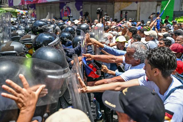 Opponents to the government of Venezuelan interim President Delcy Rodriguez confront the police as they demonstrate in demand of salary and pension raises in Caracas on April 9, 2026. (Photo by Juan BARRETO / AFP)