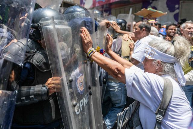 Opponents to the government of Venezuelan interim President Delcy Rodriguez confront the police as they demonstrate in demand of salary and pension raises in Caracas on April 9, 2026. (Photo by Juan BARRETO / AFP)