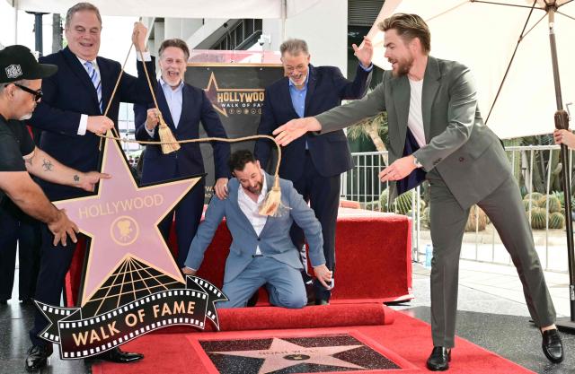 Hollywood Chamber of Commerce Chair Jerry Newman (2L), US actors Steven Weber (3L) and Jonathan Frakes (2), and US dancer Derek Hough (R) smile as US actor Noah Wyle reacts during the unveiling of his star at his Hollywood Walk of Fame ceremony in Hollywood, California, on April 9, 2026. (Photo by Frederic J. Brown / AFP)
