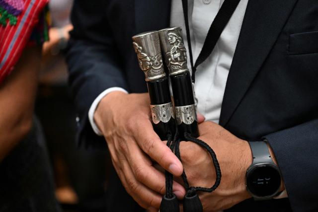 An attendee holds an indigenous authority staff while standing with their back turned in protest during a meeting of Guatemala's attorney general Consuelo Porras with the commission that nominates finalists for the election of the attorney general for the next four-year term at the Supreme Court in Guatemala City on April 9, 2026. (Photo by JOHAN ORDONEZ / AFP)