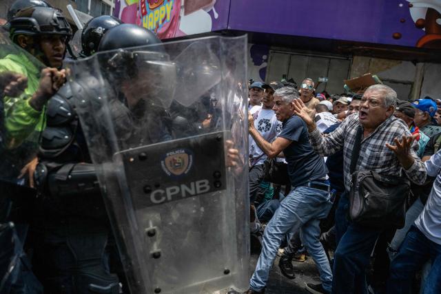 Opponents to the government of Venezuelan interim President Delcy Rodriguez clash with the police as they demonstrate in demand of salary and pension raises in Caracas on April 9, 2026. Venezuelan police fired tear gas to disperse around 2,000 protesters who marched towards the presidential palace to demand salary and pension increases, AFP reporters saw. (Photo by Juan BARRETO / AFP)