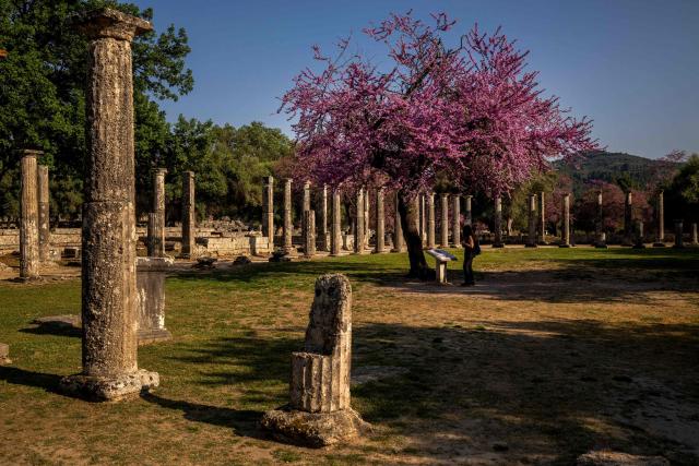 (FILES) A woman visits at the archaeological site in ancient Olympia, on April 14, 2024. From 2022 to 2025, scientists at the National University of Athens and the National Hellenic Research Foundation examined past and present climate and geological conditions at the 19 sites, looking at prior damage to help determine future vulnerability to extreme events. The sites under scrutiny include Olympia, habitually threatened by forest fires, the ancient theatre of Delphi, where rockslides are a concern. (Photo by Angelos TZORTZINIS / AFP)