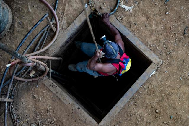 (FILES) A Venezuelan miner descends into a vertical mine held by a rope while heading to dig and extract gold in a mine, which will then be sold in El Callao, Bolivar State, Venezuela, on September 2, 2023. Venezuela's Parliament approved a mining law that opens the door for foreign investors to exploit the country's vast reserves on April 9, 2026, following a similar move regarding the oil industry under pressure from the United States. (Photo by Magda Gibelli / AFP)