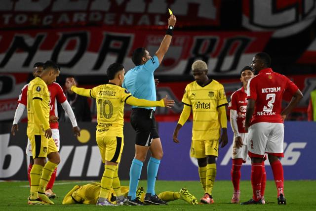 Venezuelan referee Jesus Valenzuela shows a yellow card to Santa Fe's defender #03 Victor Moreno during the Copa Libertadores group stage football match between Colombia's Independiente Santa Fe and Uruguay's Penarol at the Nemesio Camacho El Campin stadium in Bogota, on April 9, 2026. (Photo by Luis ACOSTA / AFP)
