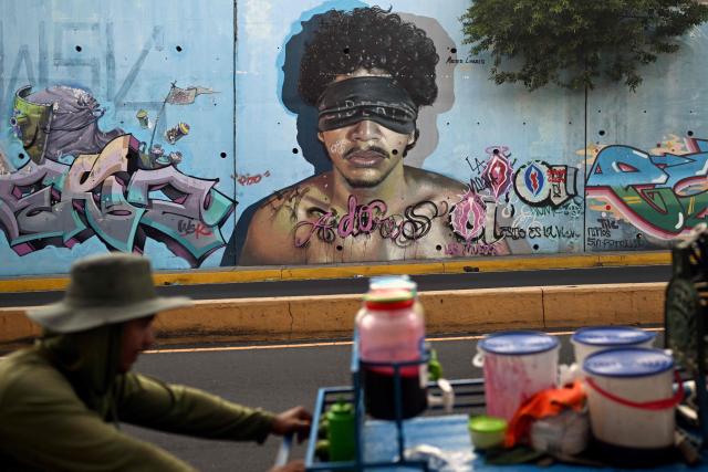 A man pushes a cart of Salvadoran minutas past a mural painted by graffiti artists on Las Amapolas Avenue in San Salvador on March 9, 2026. (Photo by Marvin RECINOS / AFP)