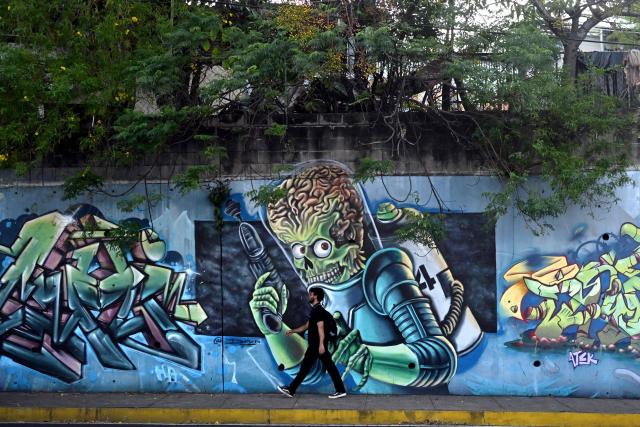A man walks past a mural painted by graffiti artists on Las Amapolas Avenue in San Salvador on March 9, 2026. (Photo by Marvin RECINOS / AFP)