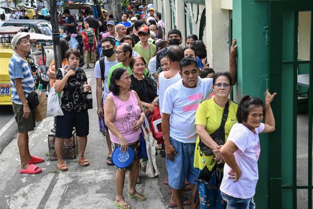 People wait in a queue outside a government-sponsored rolling store selling cheap rice near a public market in Manila on April 10, 2026. (Photo by Ted ALJIBE / AFP)