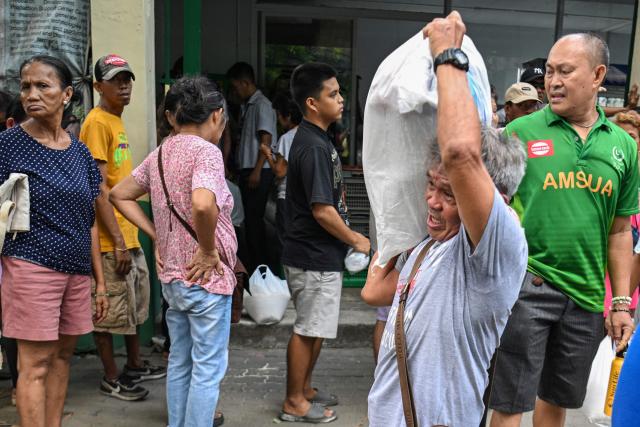 An elderly man carries a sack of rice after buying it from a government-sponsored rolling store selling cheap rice near a public market in Manila on April 10, 2026. (Photo by Ted ALJIBE / AFP)