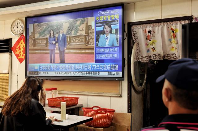 TOPSHOT - A television shows the meeting between Kuomintang (KMT) chairwoman Cheng Li-wun and Chinese President Xi Jinping in Beijing, at a restaurant in Taipei on April 10, 2026. (Photo by I-Hwa Cheng / AFP)