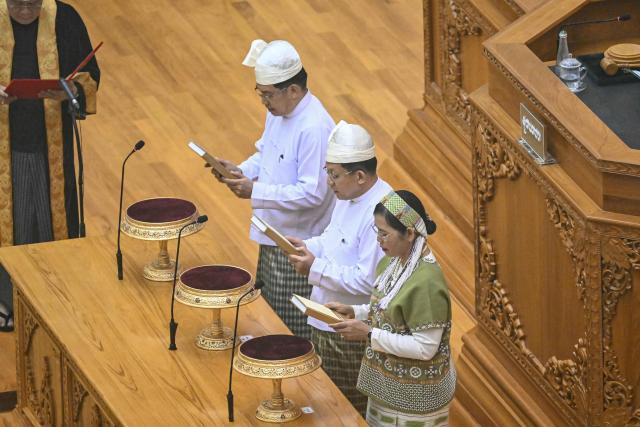 Former Myanmar military chief and Myanmar president Min Aung Hlaing (C) and vice-presidents Nyo Saw (L) and Nan Ni Ni Aye (R) attend a sworn-ing ceremony during a session of the Pyidaungsu Hluttaw (Union Parliament) in Naypyidaw on April 10, 2026. Myanmar junta chief Min Aung Hlaing was sworn in as president on April 10, 2026, AFP journalists saw, continuing his rule from a civilian post five years after snatching power in a coup. (Photo by Sai Aung MAIN / AFP)