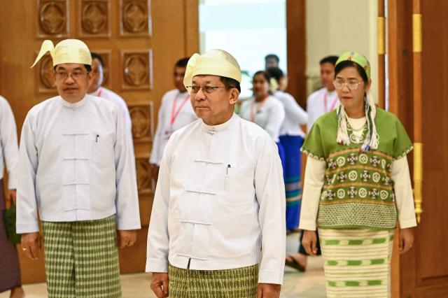 Former Myanmar military chief and Myanmar president Min Aung Hlaing (C) and vice-presidents Nyo Saw (L) and Nan Ni Ni Aye (R) arrive to attend their sworn-in ceremony during a session of the Pyidaungsu Hluttaw (Union Parliament) in Naypyidaw on April 10, 2026. Myanmar junta chief Min Aung Hlaing was sworn in as president on April 10, 2026, AFP journalists saw, continuing his rule from a civilian post five years after snatching power in a coup. (Photo by Sai Aung MAIN / AFP)