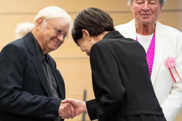 Japan’s Prime Minister Sanae Takaichi (front) shake hands with a member of British rock band Deep Purple Ian Paice (L) during a meeting at the Prime Minister’s Office in Tokyo on April 10, 2026. (Photo by Yuichi YAMAZAKI / POOL / AFP)