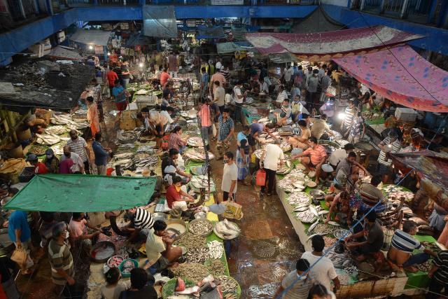 (FILES) People shop at a fish market in Kolkata on June 20, 2021 after West Bengal's state government eased lockdown restrictions to curb the spread of the Covid-19 coronavirus. In India's West Bengal state, the beloved fish has leapt from the kitchen table to the campaign trail, becoming an unexpected flashpoint in a fiercely contested election. Now, as the state of over 100 million people gears up for polls on April 23 and 29, 2026 the slippery staple has also become political ammunition. (Photo by Mainak BAGCHI / AFP)