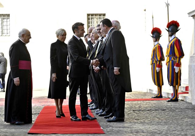 France's President Emmanuel Macron and his wife Brigitte Macron are welcomed by officials as they arrive in San Damaso courtyard before a meeting with Pope Leo XIV, in the Vatican on April 10, 2026. (Photo by Tiziana FABI / AFP)