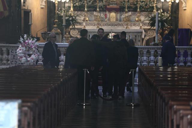 French singer, performer and Elvis Presley look-alike Eryl Prayer (C) is comforted as he arrives to attend the funeral ceremony of Loana Petrucciani, the first reality TV star in France, at the cathedral of Sainte-Reparate in Nice, southeastern France where she was found dead at her home at the age of 48, on April 10, 2026. (Photo by Thibaud MORITZ / AFP)
