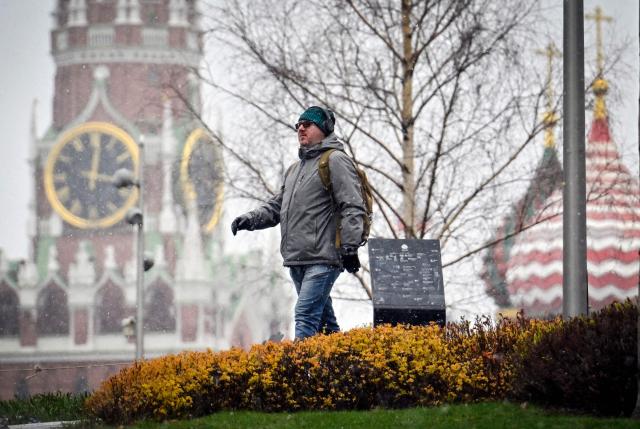 A man walks in front of the Kremlin's Spasskaya tower (L) and St. Basil's cathedral in downtown Moscow on April 10, 2026. (Photo by Alexander NEMENOV / AFP)