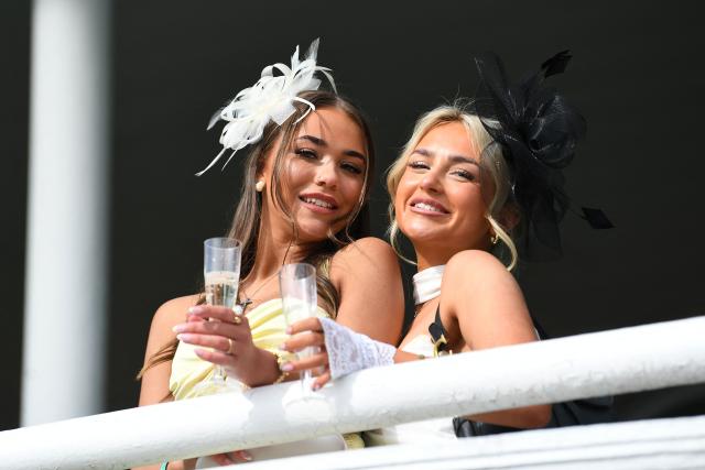 Racegoers pose in the sunshine on Ladies Day, day two of the Grand National Festival horse race meeting at Aintree Racecourse in Liverpool, north-west England, on April 10, 2026. (Photo by PETER POWELL / AFP)