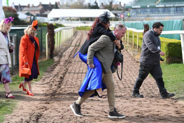 Racegoers cross the racecourse in the sunshine on Ladies Day, day two of the Grand National Festival horse race meeting at Aintree Racecourse in Liverpool, north-west England, on April 10, 2026. (Photo by PETER POWELL / AFP)
