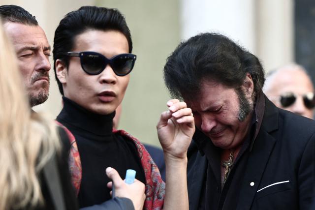 French singer, performer and Elvis Presley look-alike Eryl Prayer (R) reacts next to French model Jeremy Bellet (2n-L) as they leave after attending the funeral ceremony of Loana Petrucciani, the first reality TV star in France, at the cathedral of Sainte-Reparate in Nice, southeastern France where she was found dead at her home at the age of 48, on April 10, 2026. (Photo by Thibaud MORITZ / AFP)
