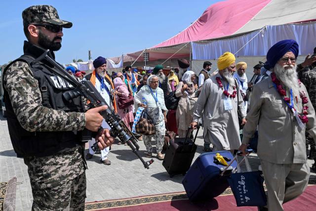 A security personnel stands guard as Indian Sikh pilgrims arrive to celebrate Baisakhi, the annual spring harvest festival in Pakistan, after crossing the India-Pakistan Wagah border on April 10, 2026. (Photo by Arif ALI / AFP)