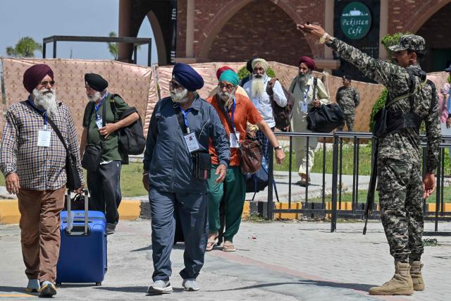 A security personnel stands guard as Indian Sikh pilgrims arrive to celebrate Baisakhi, the annual spring harvest festival in Pakistan, after crossing the India-Pakistan Wagah border on April 10, 2026. (Photo by Arif ALI / AFP)