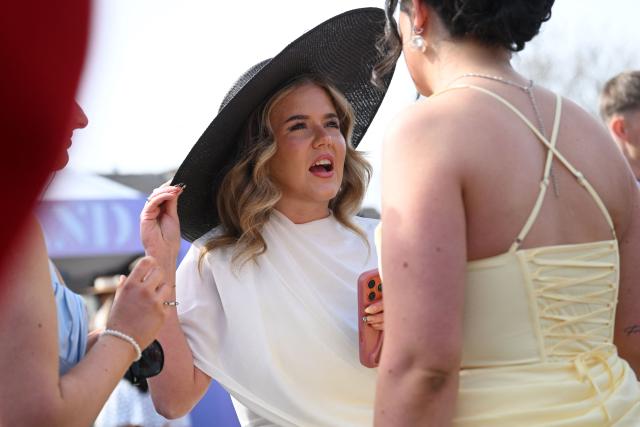 Racegoers mingle in the sunshine on Ladies Day, day two of the Grand National Festival horse race meeting at Aintree Racecourse in Liverpool, north-west England, on April 10, 2026. (Photo by Paul ELLIS / AFP)