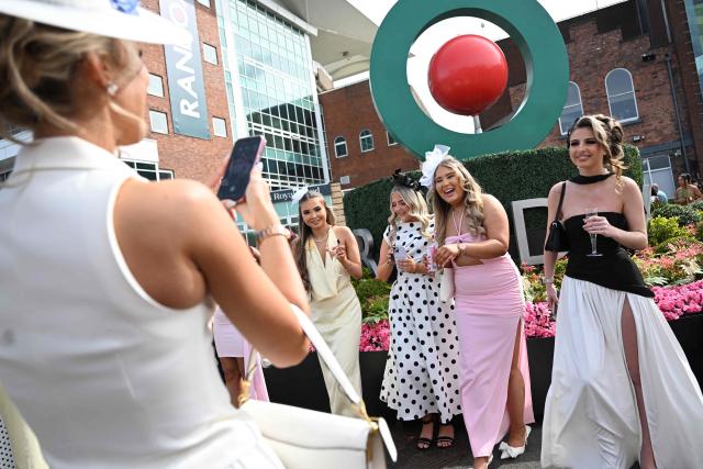 Racegoers pose in the sunshine on Ladies Day, day two of the Grand National Festival horse race meeting at Aintree Racecourse in Liverpool, north-west England, on April 10, 2026. (Photo by Paul ELLIS / AFP)