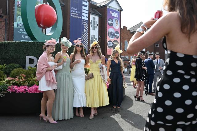 Racegoers pose in the sunshine on Ladies Day, day two of the Grand National Festival horse race meeting at Aintree Racecourse in Liverpool, north-west England, on April 10, 2026. (Photo by Paul ELLIS / AFP)