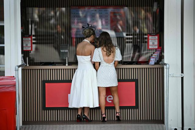 Racegoers place a bet at the Tote on Ladies Day, day two of the Grand National Festival horse race meeting at Aintree Racecourse in Liverpool, north-west England, on April 10, 2026. (Photo by Paul ELLIS / AFP)