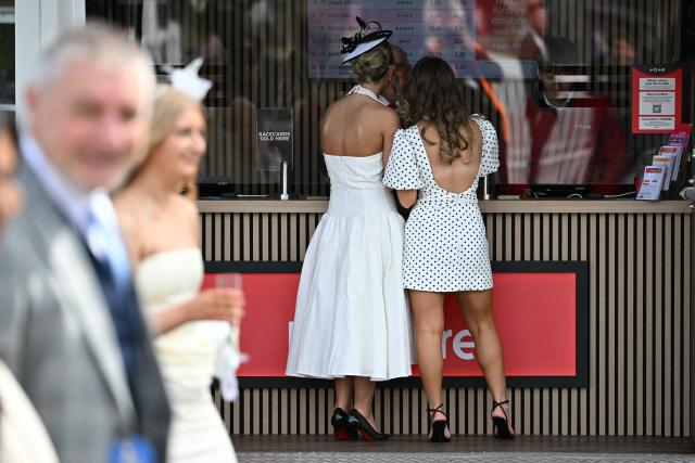 Racegoers place a bet at the Tote on Ladies Day, day two of the Grand National Festival horse race meeting at Aintree Racecourse in Liverpool, north-west England, on April 10, 2026. (Photo by Paul ELLIS / AFP)