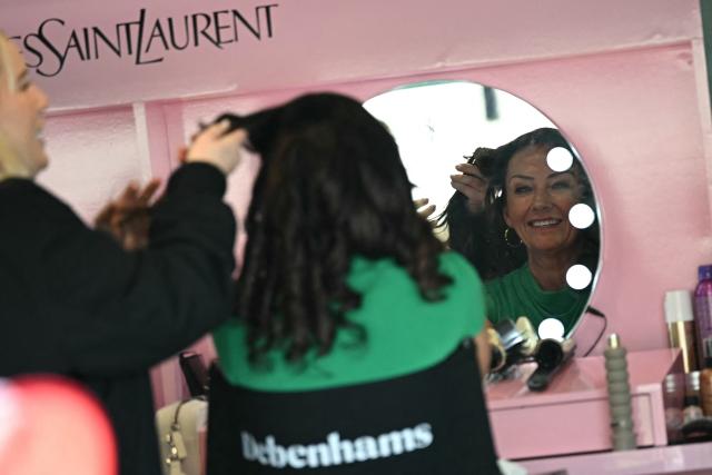 A racegoer has her hair done on Ladies Day, day two of the Grand National Festival horse race meeting at Aintree Racecourse in Liverpool, north-west England, on April 10, 2026. (Photo by Paul ELLIS / AFP)