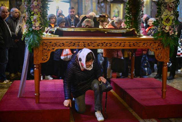 East-Orthodox believer passes under a table where the Bible is placed during the Good Friday service in St Nedelya Church in Sofia on April 10, 2026. (Photo by Nikolay DOYCHINOV / AFP)