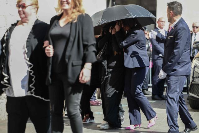 Violette Petrucciani (L) and Maelysse and Mindy, granddaughter and daughter of Loana, hidden under an umbrella, arrive to attend the funeral ceremony of Loana Petrucciani, the first reality TV star in France, at the cathedral of Sainte-Reparate in Nice, southeastern France where she was found dead at her home at the age of 48, on April 10, 2026. (Photo by Thibaud MORITZ / AFP)