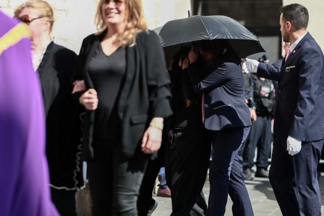 Violette Petrucciani (L) and Maelysse and Mindy, granddaughter and daughter of Loana, hidden under an umbrella, arrive to attend the funeral ceremony of Loana Petrucciani, the first reality TV star in France, at the cathedral of Sainte-Reparate in Nice, southeastern France where she was found dead at her home at the age of 48, on April 10, 2026. (Photo by Thibaud MORITZ / AFP)