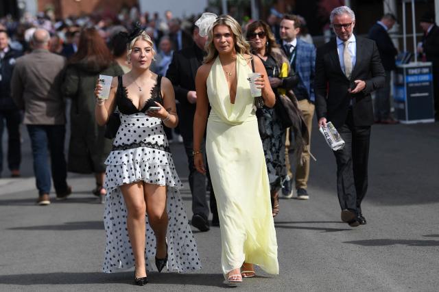 Racegoers walk in the sunshine on Ladies Day, day two of the Grand National Festival horse race meeting at Aintree Racecourse in Liverpool, north-west England, on April 10, 2026. (Photo by PETER POWELL / AFP)