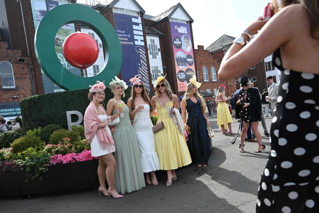 Racegoers pose for a picture on Ladies Day, day two of the Grand National Festival horse race meeting at Aintree Racecourse in Liverpool, north-west England, on April 10, 2026. (Photo by Paul ELLIS / AFP)