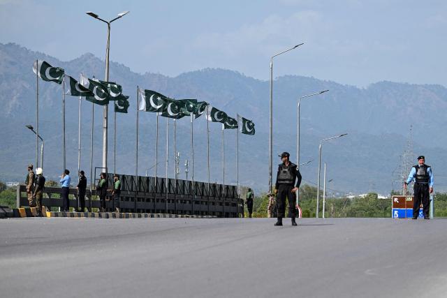 Security personnel stand guard on a bridge as a motorcade carrying US security officials makes its way toward the venue of the US–Iran talks in Islamabad on April 10, 2026. A cloud of uncertainty hung on April 10 over the scheduled start of talks in Pakistan between the United States and Iran, with no announcement yet on the arrival of negotiators and both sides accusing the other of failing to properly implement a fragile ceasefire. (Photo by Aamir QURESHI / AFP)