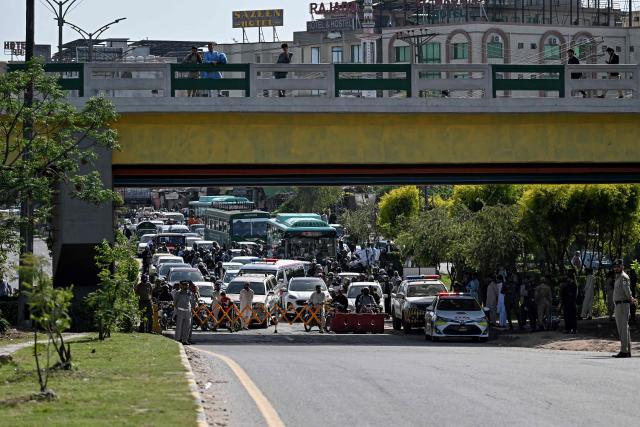 Security personnel halt traffic as motorcade vehicles carrying US security officials make their way toward the venue of the US–Iran talks in Islamabad on April 10, 2026. A cloud of uncertainty hung on April 10 over the scheduled start of talks in Pakistan between the United States and Iran, with no announcement yet on the arrival of negotiators and both sides accusing the other of failing to properly implement a fragile ceasefire. (Photo by Aamir QURESHI / AFP)