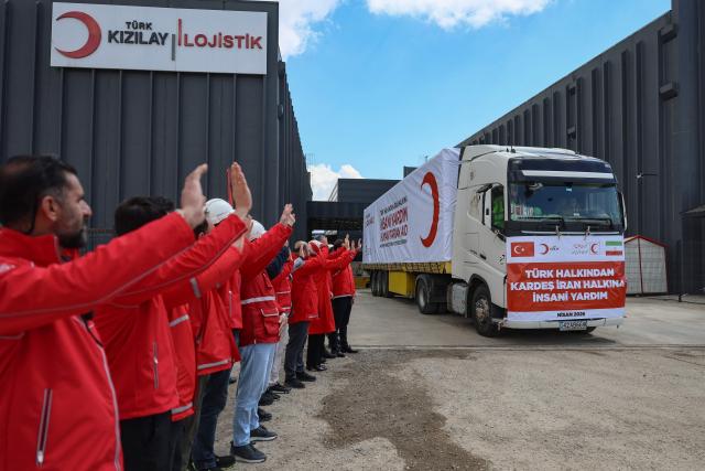 Workers wave as a truck of The Red Cross and Turkey's Red Crescent leaves to send supplies to Iran, in Ankara on April 10, 2026. The Red Cross and Turkey's Red Crescent on Friday dispatched an emergency humanitarian aid convoy from Turkey to Iran, as the organisation warned of a "desperate" humanitarian situation in the country. (Photo by Adem ALTAN / AFP)